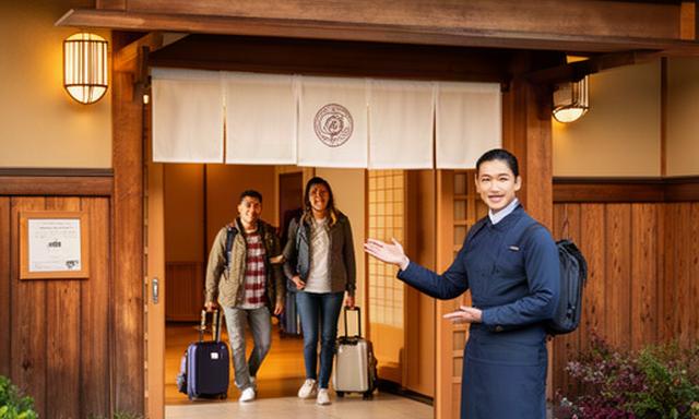伊豆の温泉旅館で外国人旅行者を迎えるスタッフと木造の玄関